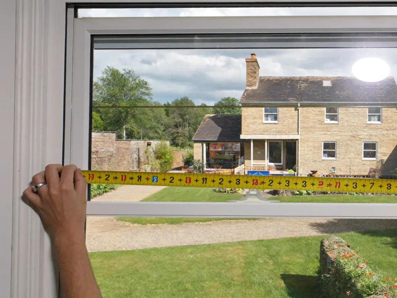 Surveyor measuring a window opening with a laser tool during a home visit
